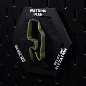 Watkins Glen hex three quarter view, the whole olive lap sharp against black pegboard