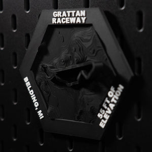 Grattan Raceway hex angled on pegboard, white engraved lettering reading Belding, MI down the left edge