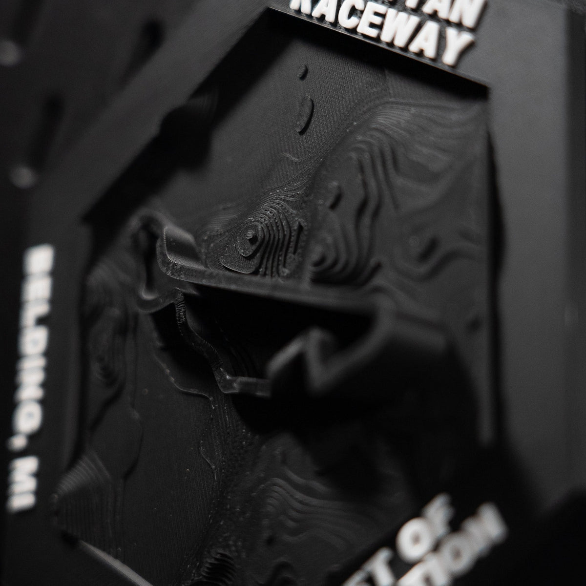 Grattan Raceway hex in close macro, the black track ribbon lifting clear of the black contour terrain
