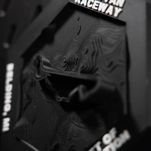 Grattan Raceway hex in close macro, the black track ribbon lifting clear of the black contour terrain