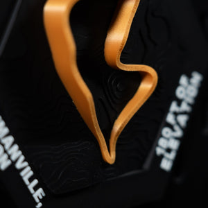 Mosport hex angled close, orange loop beside engraved lettering reading Bowmanville, ON