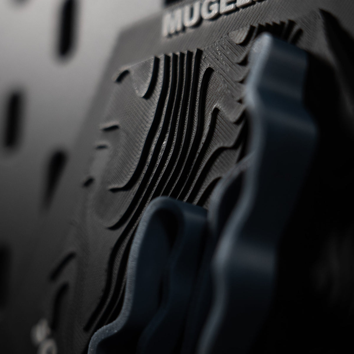 Mugello hex at a raking angle, dense contour ridges running beneath the engraved name