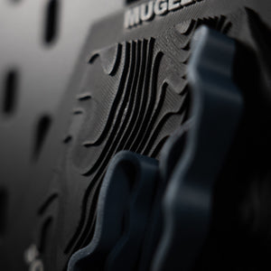 Mugello hex at a raking angle, dense contour ridges running beneath the engraved name