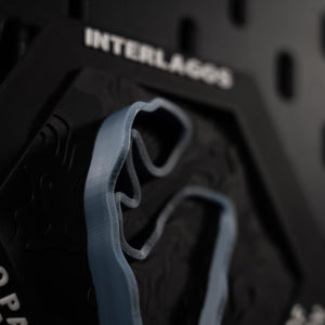 Interlagos hex at an angle, blue ribbon curving below the engraved circuit name