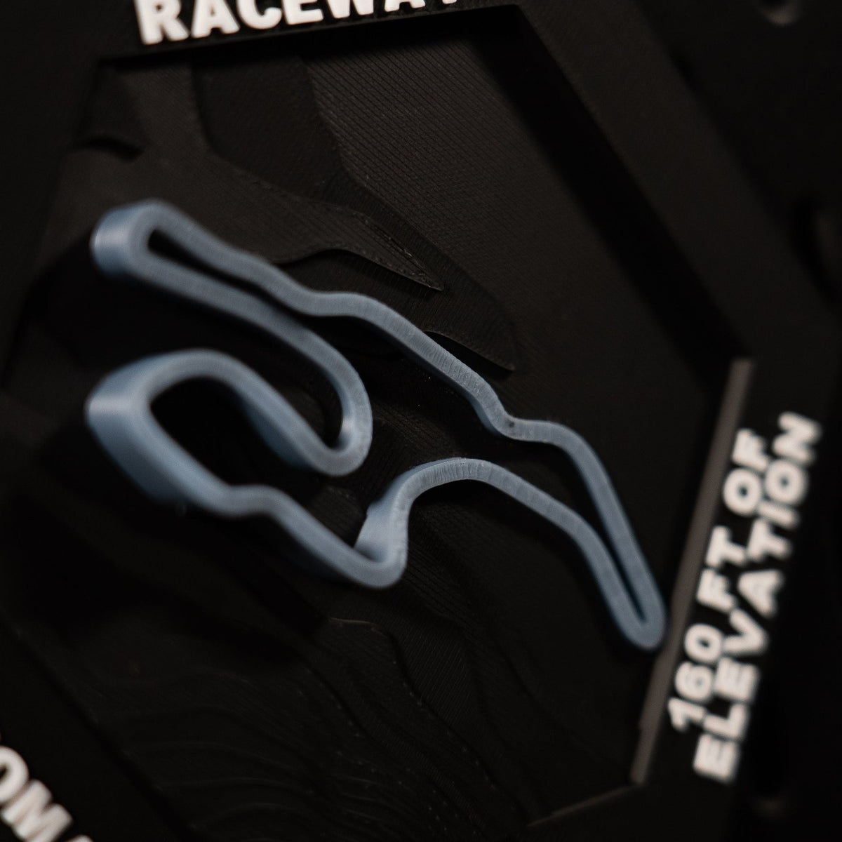 Sonoma Raceway hex from above, blue esses in relief beside the engraved 160 ft of elevation