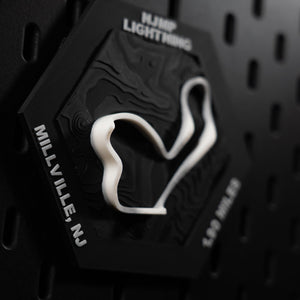 NJMP Lightning hex macro, white ribbon coiling past the engraved 1.90 miles