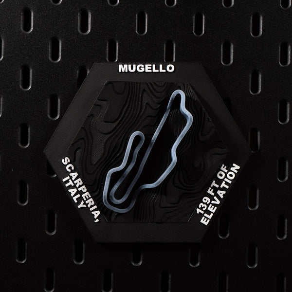 Mugello hex flat on black pegboard, slate blue circuit loop on dark terraced terrain