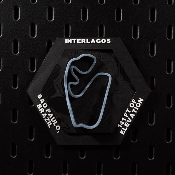 Interlagos hex flat on black pegboard, pale blue track loop set into dark contour terrain