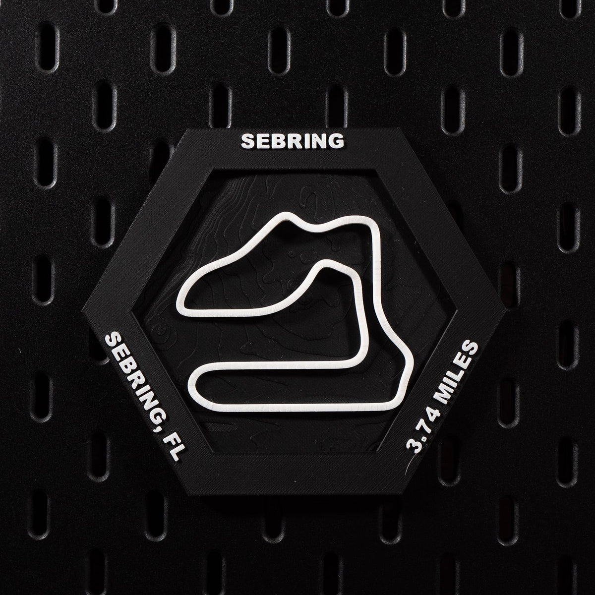 Sebring hex flat on black pegboard, white circuit loop over black contour terrain