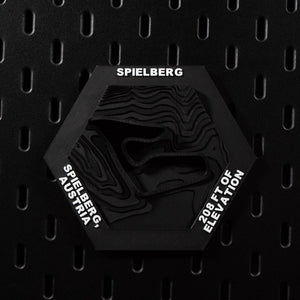 Spielberg hex flat on black pegboard, black on black with the circuit cut into terraced terrain