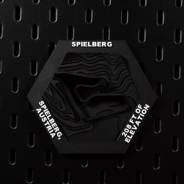 Spielberg hex flat on black pegboard, black on black with the circuit cut into terraced terrain