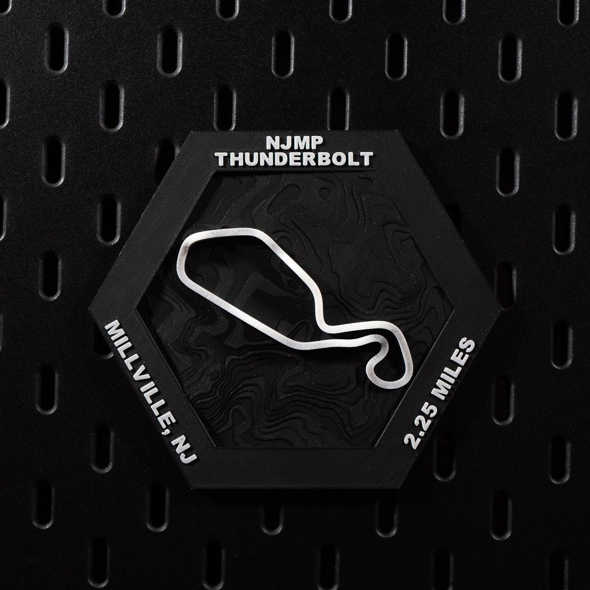 NJMP Thunderbolt hex flat on black pegboard, white circuit loop over black contour terrain