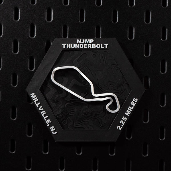 NJMP Thunderbolt hex flat on black pegboard, white circuit loop over black contour terrain