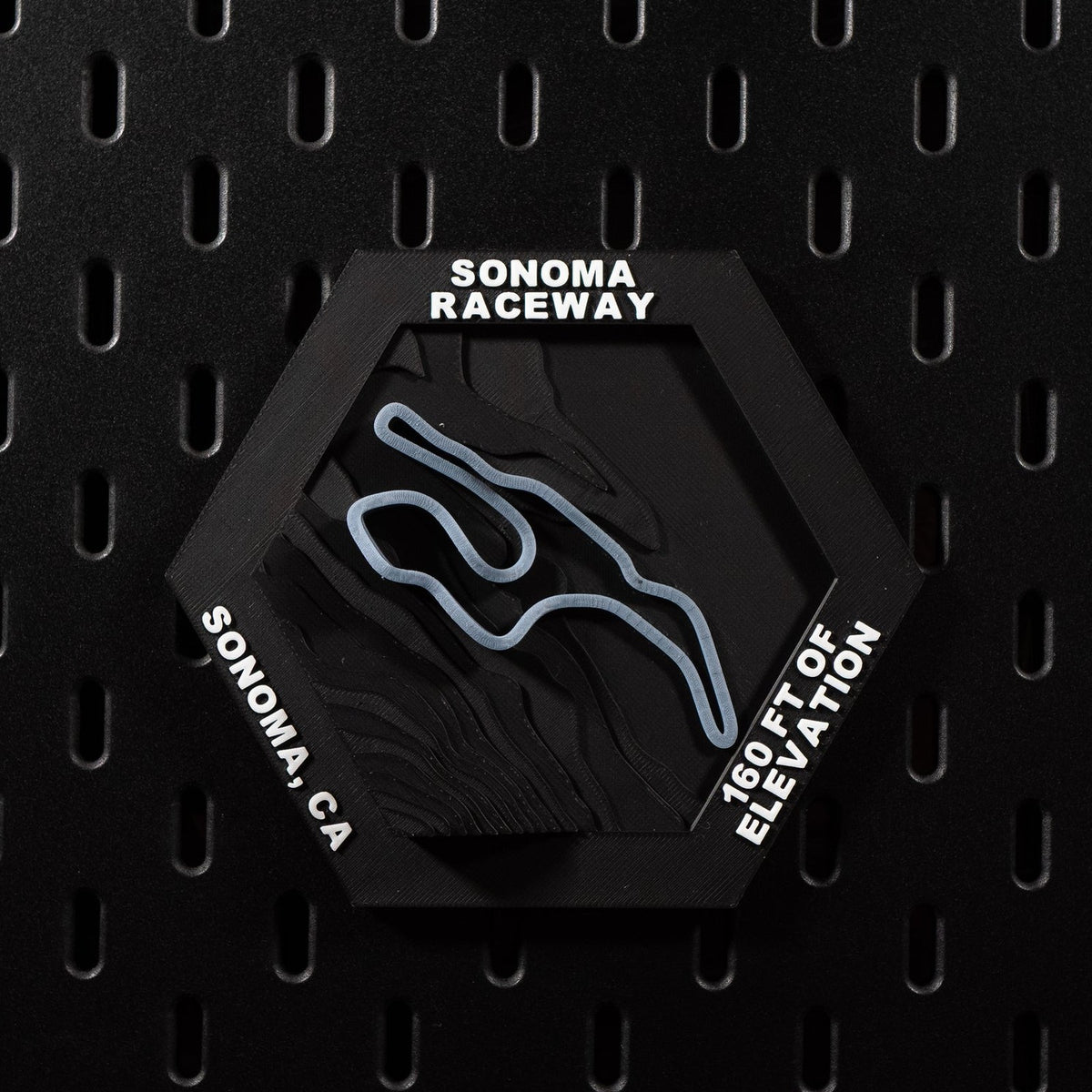 Sonoma Raceway hex flat on black pegboard, steel blue circuit loop on terraced terrain